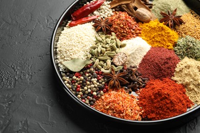 Photo of Different aromatic spices on dark textured table, closeup