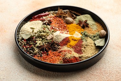 Photo of Different aromatic spices on beige textured table, closeup