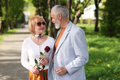 Photo of Lovely senior couple with rose in park