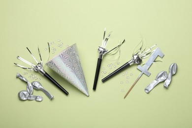 Photo of Flat lay composition with party hat and blowers on light green background