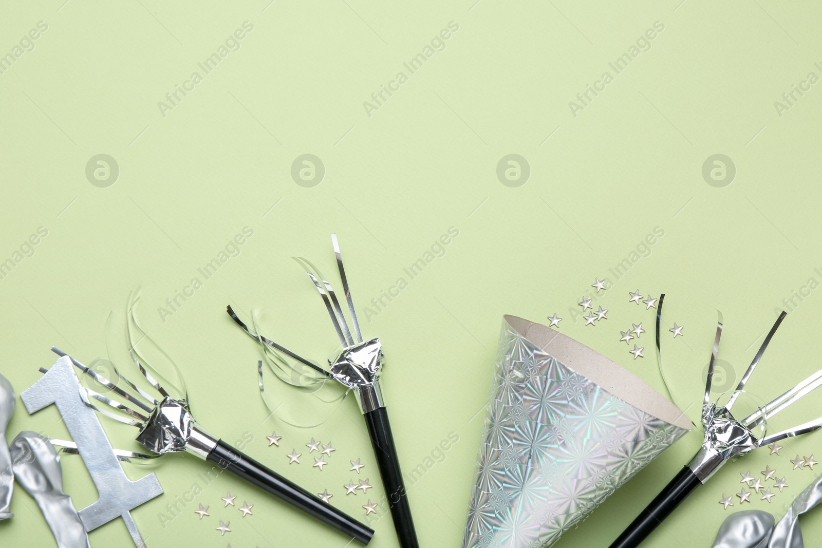 Flat lay composition with party hat and blowers on light green background. Space for text Photo of Flat lay composition with party hat and blowers on light green background. Space for text