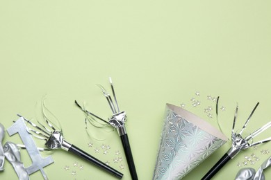 Photo of Flat lay composition with party hat and blowers on light green background. Space for text