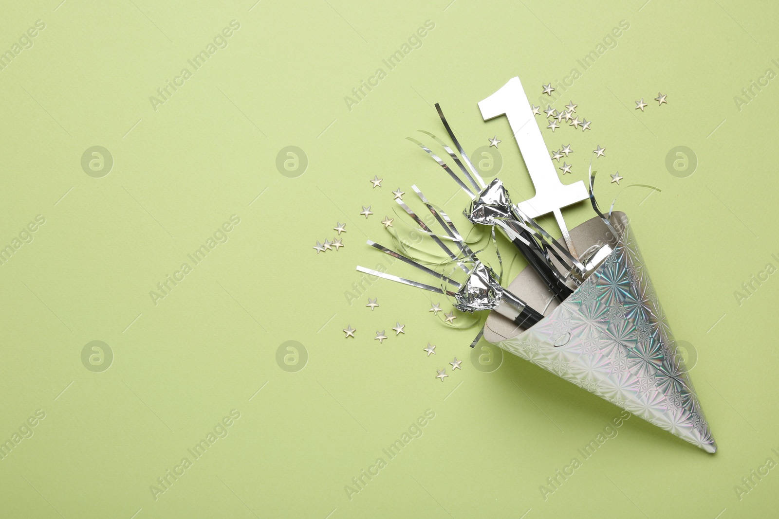 Party hat, blowers, topper and confetti on light green background, top view. Space for text Photo of Party hat, blowers, topper and confetti on light green background, top view. Space for text