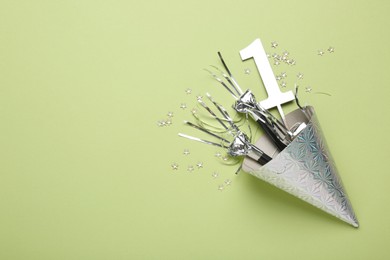 Photo of Party hat, blowers, topper and confetti on light green background, top view. Space for text