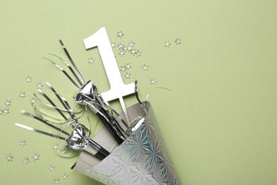 Photo of Party hat, blowers, topper and confetti on light green background, top view. Space for text