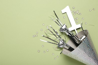 Photo of Party hat, blowers, topper and confetti on light green background, top view. Space for text