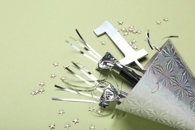 Photo of Party hat, blowers, topper and confetti on light green background, closeup