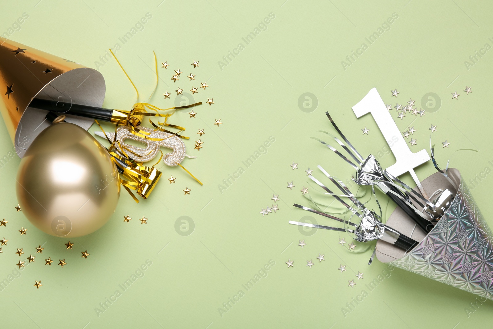 Flat lay composition with party hats and blowers on light green background Photo of Flat lay composition with party hats and blowers on light green background