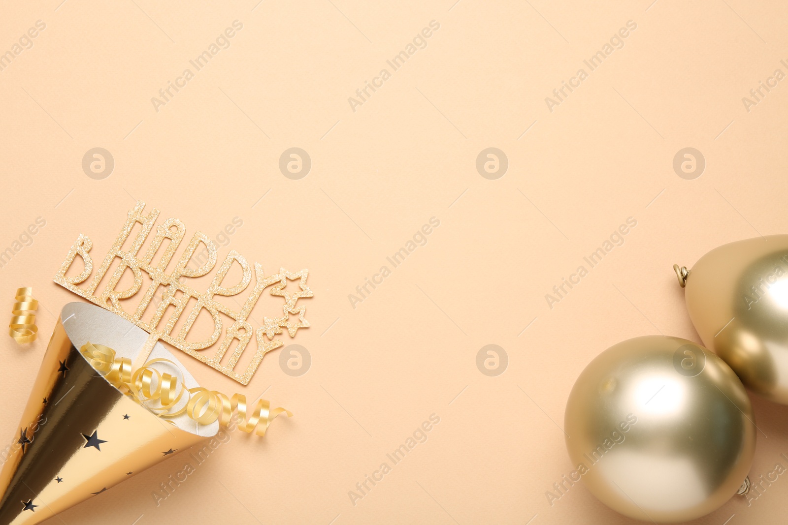Party hat, topper, streamers and balloons on beige background, flat lay. Space for text Photo of Party hat, topper, streamers and balloons on beige background, flat lay. Space for text