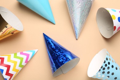 Photo of Colorful party hats on beige background, flat lay