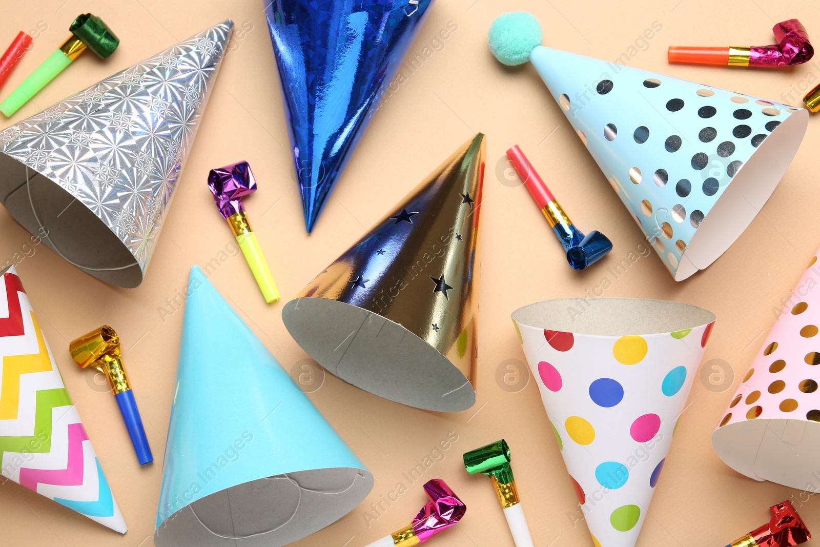 Colorful party hats and streamers on beige background, flat lay Photo of Colorful party hats and streamers on beige background, flat lay