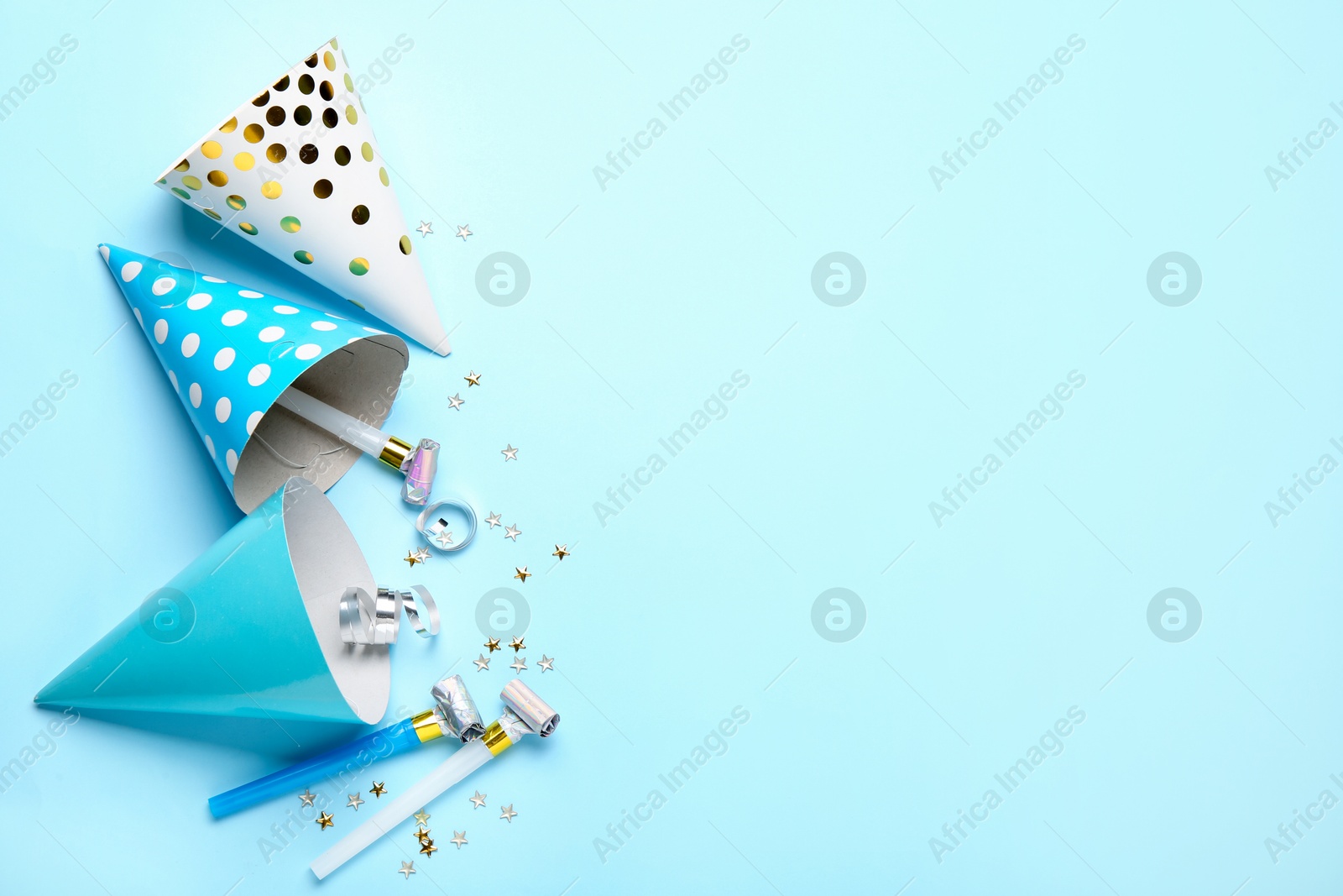 Flat lay composition with party hats and blowers on light blue background. Space for text Photo of Flat lay composition with party hats and blowers on light blue background. Space for text