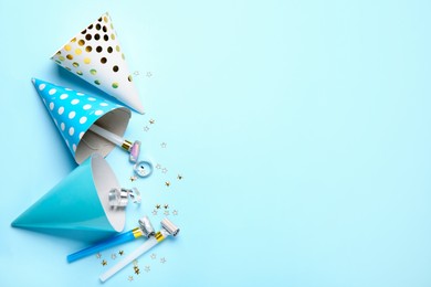Photo of Flat lay composition with party hats and blowers on light blue background. Space for text