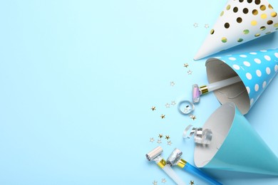 Photo of Flat lay composition with party hats and blowers on light blue background. Space for text