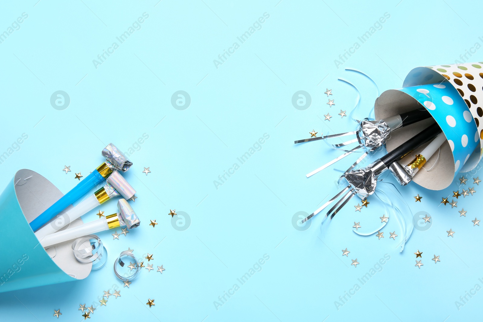 Flat lay composition with party hats and blowers on light blue background. Space for text Photo of Flat lay composition with party hats and blowers on light blue background. Space for text