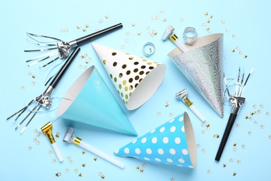Photo of Flat lay composition with party hats and confetti on light blue background