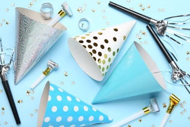 Photo of Flat lay composition with party hats and confetti on light blue background