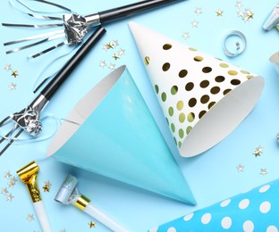 Photo of Flat lay composition with party hats and confetti on light blue background