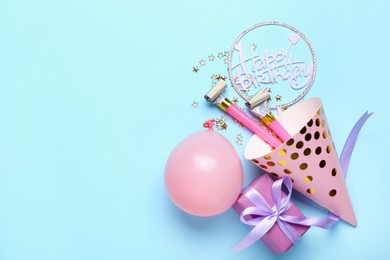 Photo of Party hat, topper, blowers, gift box and balloon on light blue background, flat lay. Space for text