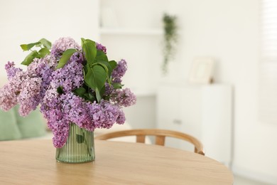 Photo of Beautiful lilac flowers in vase on wooden table indoors, space for text