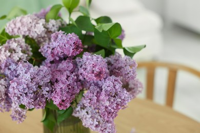 Photo of Beautiful lilac flowers in vase on table indoors, closeup. Space for text