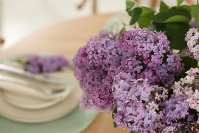 Photo of Beautiful lilac flowers on table, closeup. Space for text