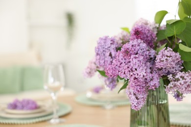 Photo of Beautiful lilac flowers in vase on table, closeup. Space for text