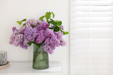 Photo of Beautiful lilac flowers in vase on table indoors, space for text