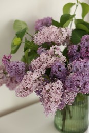 Photo of Beautiful lilac flowers in vase on table indoors, closeup