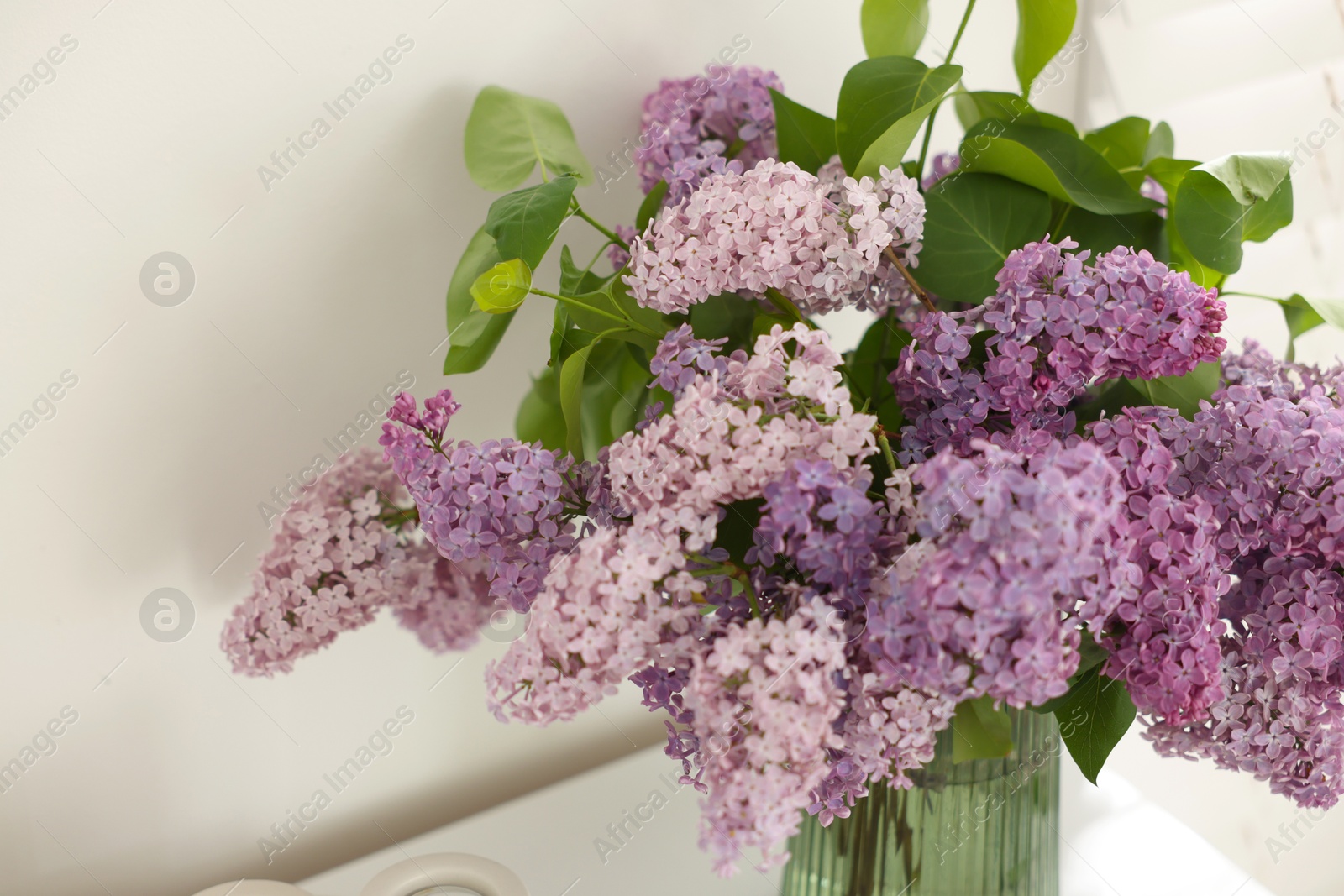 Beautiful lilac flowers in vase on table indoors, closeup Photo of Beautiful lilac flowers in vase on table indoors, closeup