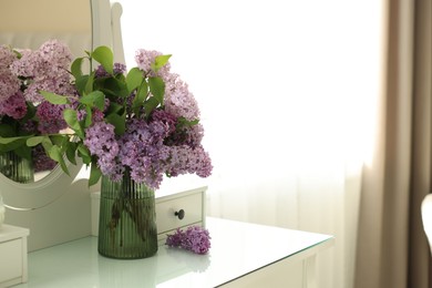 Photo of Beautiful lilac flowers in vase on dressing table indoors, space for text