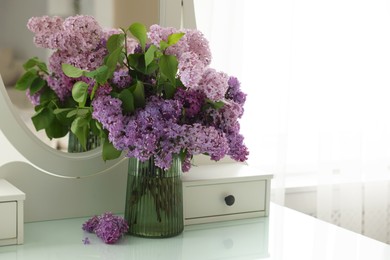 Photo of Beautiful lilac flowers in vase on dressing table indoors