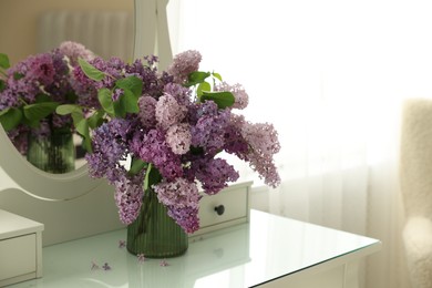 Photo of Beautiful lilac flowers in vase on dressing table indoors, space for text