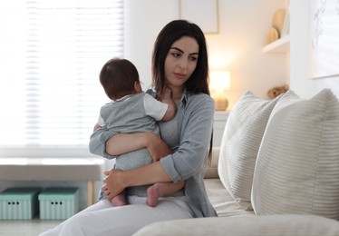 Photo of Woman suffering from postpartum depression with her little baby on sofa at home