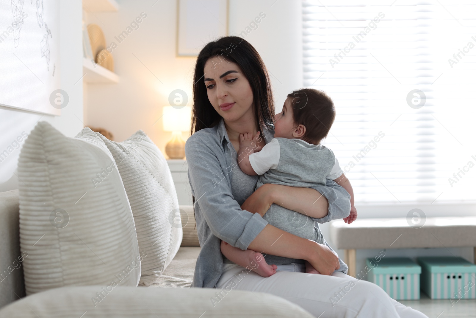 Woman suffering from postpartum depression with her little baby on sofa at home Photo of Woman suffering from postpartum depression with her little baby on sofa at home