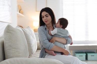 Photo of Woman suffering from postpartum depression with her little baby on sofa at home