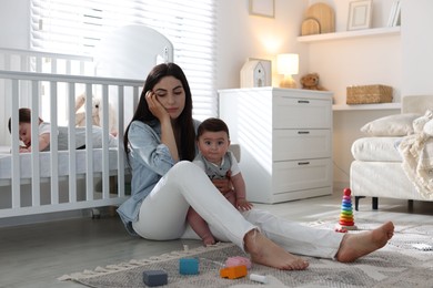 Photo of Woman suffering from postpartum depression with her little children at home. Space for text
