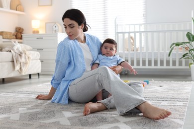 Photo of Woman suffering from postpartum depression with her little baby at home