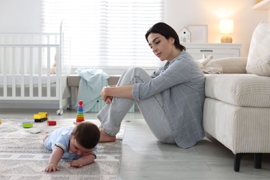 Photo of Woman suffering from postpartum depression with her little baby at home. Space for text