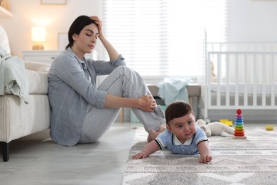 Photo of Woman suffering from postpartum depression with her little baby at home. Space for text