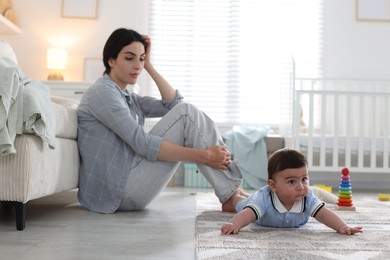 Photo of Woman suffering from postpartum depression with her little baby at home. Space for text