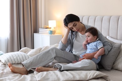 Photo of Woman suffering from postpartum depression with her little baby on bed at home. Space for text
