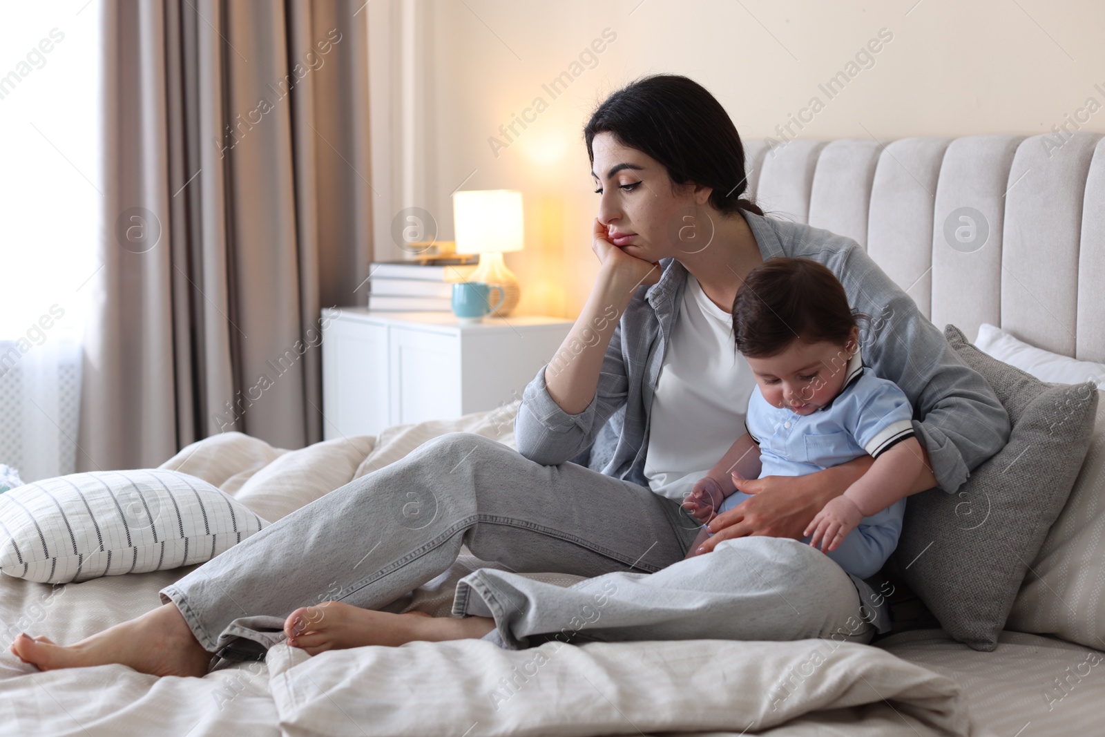 Woman suffering from postpartum depression with her little baby on bed at home. Space for text Photo of Woman suffering from postpartum depression with her little baby on bed at home. Space for text