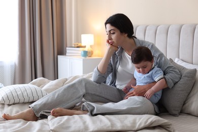 Photo of Woman suffering from postpartum depression with her little baby on bed at home. Space for text