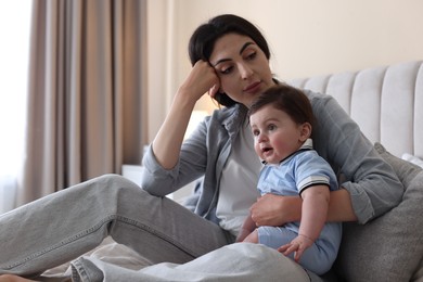 Photo of Woman suffering from postpartum depression with her little baby on bed at home. Space for text