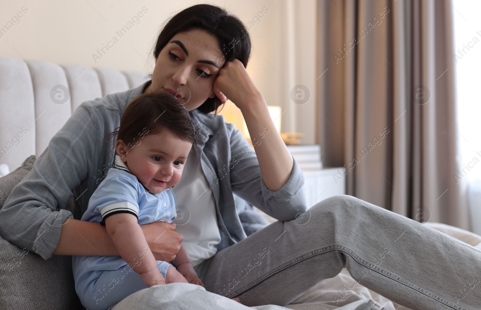 Woman suffering from postpartum depression with her little baby on bed at home. Space for text Photo of Woman suffering from postpartum depression with her little baby on bed at home. Space for text