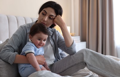 Photo of Woman suffering from postpartum depression with her little baby on bed at home. Space for text