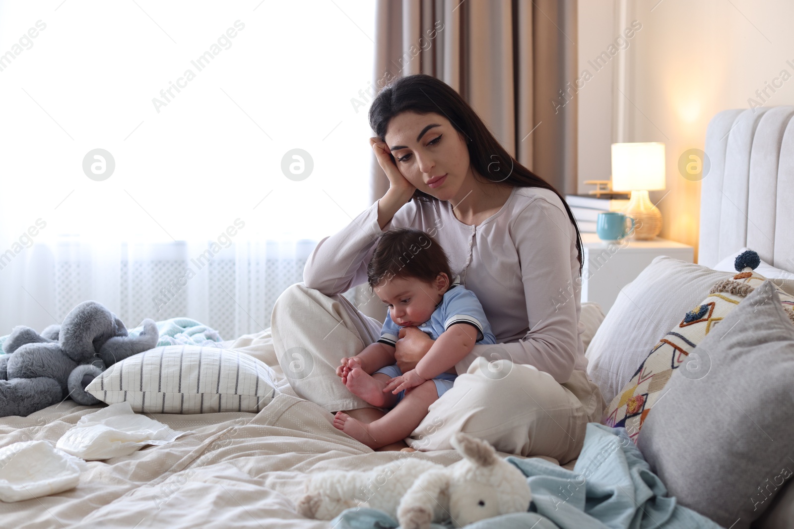 Woman suffering from postpartum depression with her little baby on bed at home. Space for text Photo of Woman suffering from postpartum depression with her little baby on bed at home. Space for text