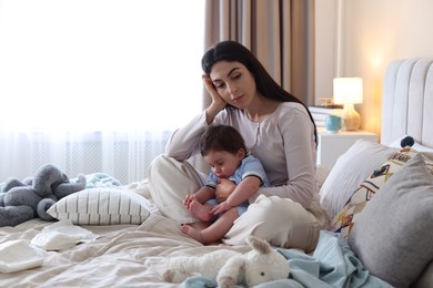 Photo of Woman suffering from postpartum depression with her little baby on bed at home. Space for text