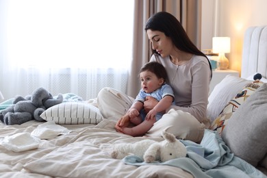 Photo of Woman suffering from postpartum depression with her little baby on bed at home. Space for text